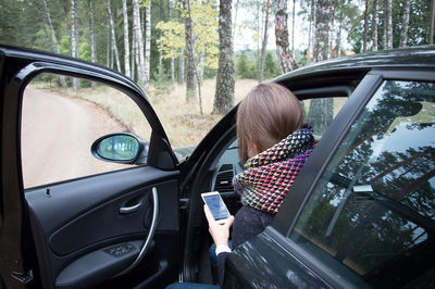 Woman using phone while sitting in car