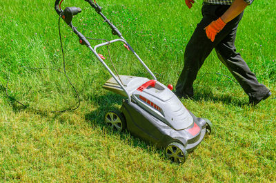 Man goes to mow grass with electric lawn mower. freshly mown grass.