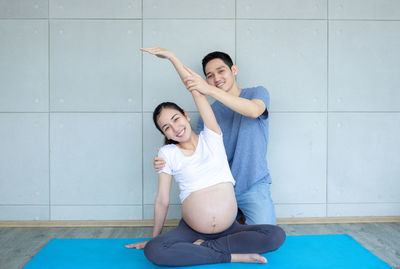 Dad is helping pregnant mothers exercise. and doing yoga in the living room