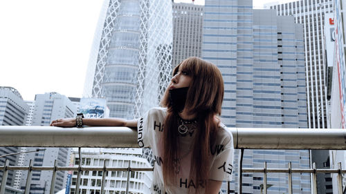 Full length of woman standing against modern buildings in city