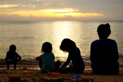 Rear view of two people sitting on beach