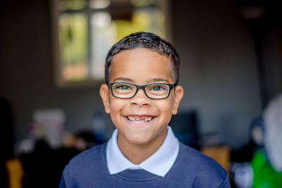 Close-up portrait of happy boy wearing eyeglasses while standing at home