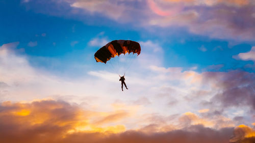 Low angle view of man paragliding against sky