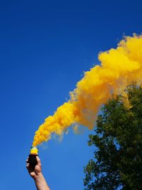 Low angle view of man hand against clear blue sky