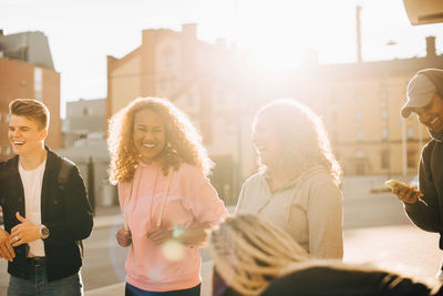 Cheerful friends enjoying together in city during sunny day