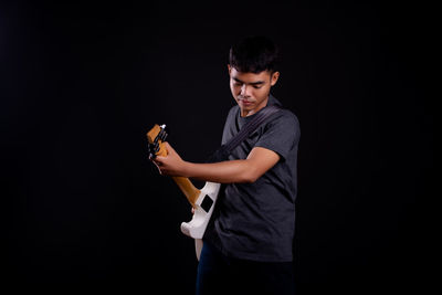 Side view of a young man against black background