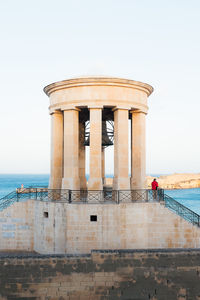 Bell in structure by sea against sky