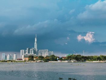 Sea by modern buildings against sky in city