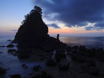 Rock formation on sea against sky during sunset