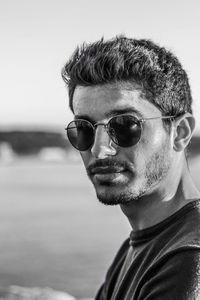 Close-up portrait of young man wearing sunglasses against sky