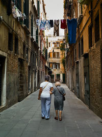 Rear view of woman walking on street amidst buildings