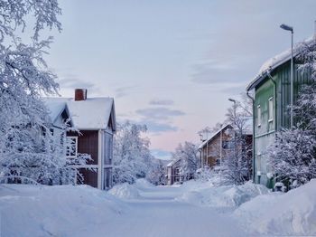 House by frozen trees against sky during winter