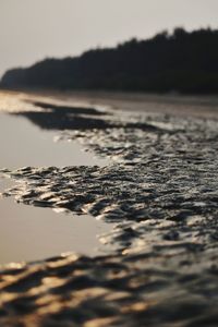 Surface level of beach against sky during sunset