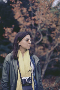 Woman wearing sunglasses standing against trees in forest