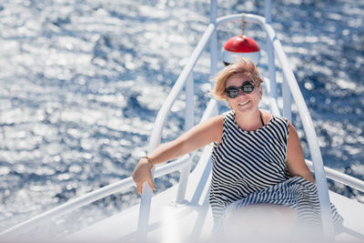 Woman relaxing on the nose of the yacht at a sunny summer day at sea