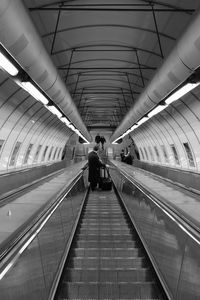 Rear view of man standing on escalator at subway station