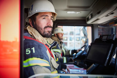 Firefighter looking through window while sitting in fire truck