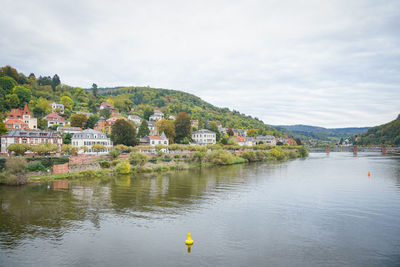 Scenic view of river by buildings against sky