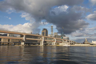 Bridge over river by buildings against sky