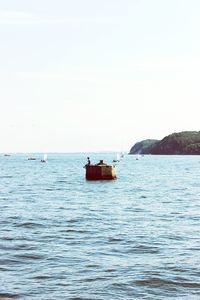 Boat sailing in sea against clear sky