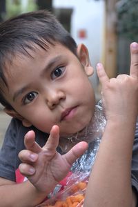 Close-up portrait of cute boy gesturing horn sign