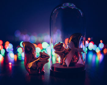 Close-up of squirrel figurines by illuminated colorful lighting equipment on table