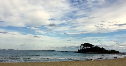 Scenic view of beach against cloudy sky