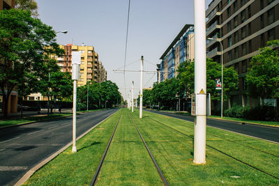 Railroad tracks by buildings in city against clear sky