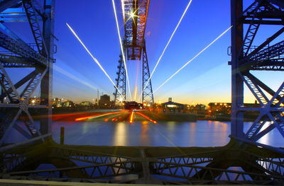 Illuminated bridge against blue sky at night