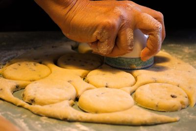 Close-up of human hand cutting dough on table