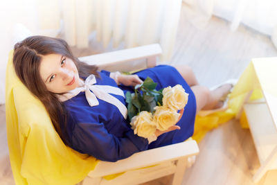 Side view of young woman sitting on bed at home