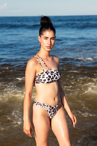 Portrait of woman in bikini standing at beach