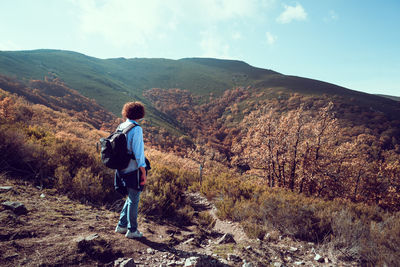 Full length of backpacker looking at mountains against sky