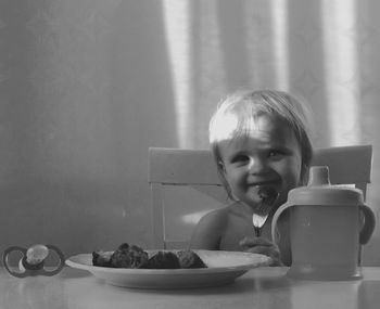 Toddler having food while sitting at table