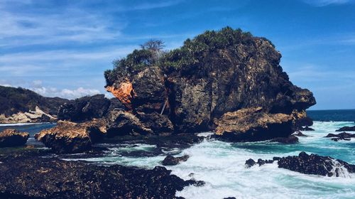 Rock formation on beach against sky