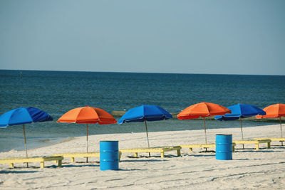 Deck chairs and parasols on beach against clear sky