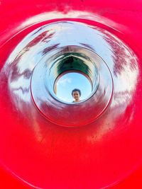 Portrait of boy seen from circular red slide in park