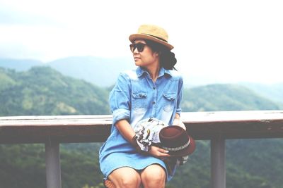 Woman sitting by railing at observation point
