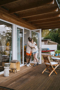 Multiracial couple embracing each other while standing on porch near doorway