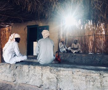 Rear view of people sitting on wall