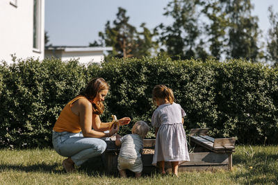 Side view of mother spending leisure time with son and daughter in back yard