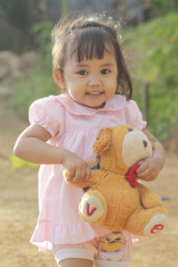 Portrait of cute girl with toy standing outdoors