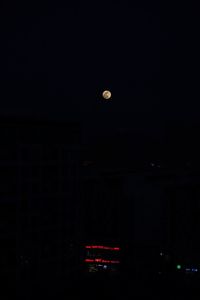 Low angle view of moon in city at night