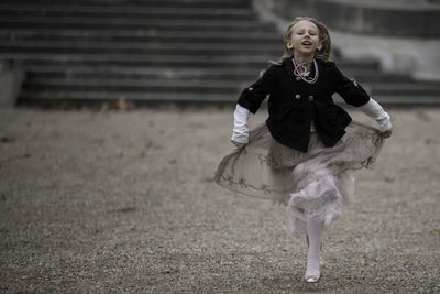 Stylishly and fashionably dressed girl in a dynamic photo while running against an antique 