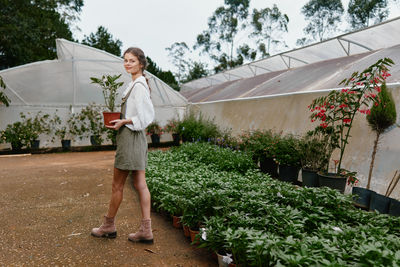 Full length of young woman standing by plants