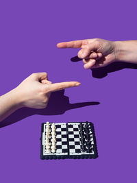 Cropped hand of woman using calculator against blue background