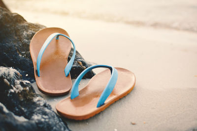 Close-up view of flip-flop on sand at beach