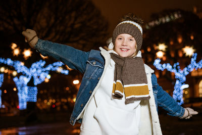 Portrait of joyful caucasian teenager boy standing on street in evening in city