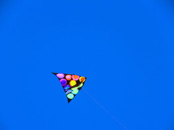 Low angle view of kite flying against clear blue sky