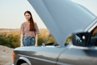 Side view of young woman holding car